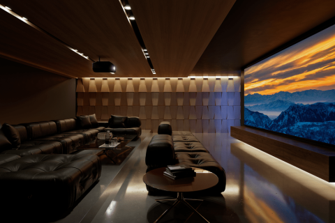 A spacious, luxurious home theater lit with warm tones showing a mountain range on the screen.